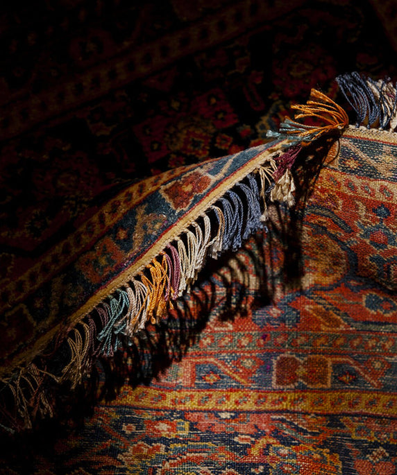 Close-up of a patterned rug with fringes on a dark background
